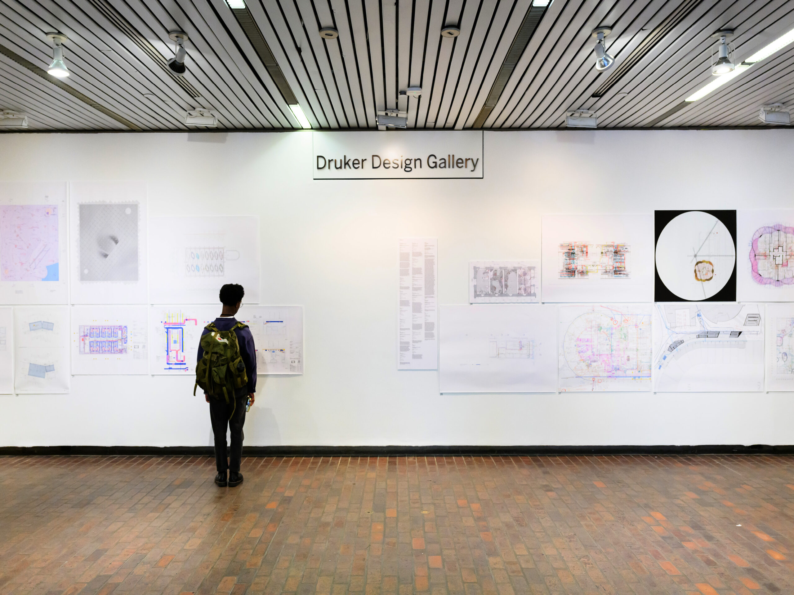 Photograph of student looking at exhibition of drawings in lobby