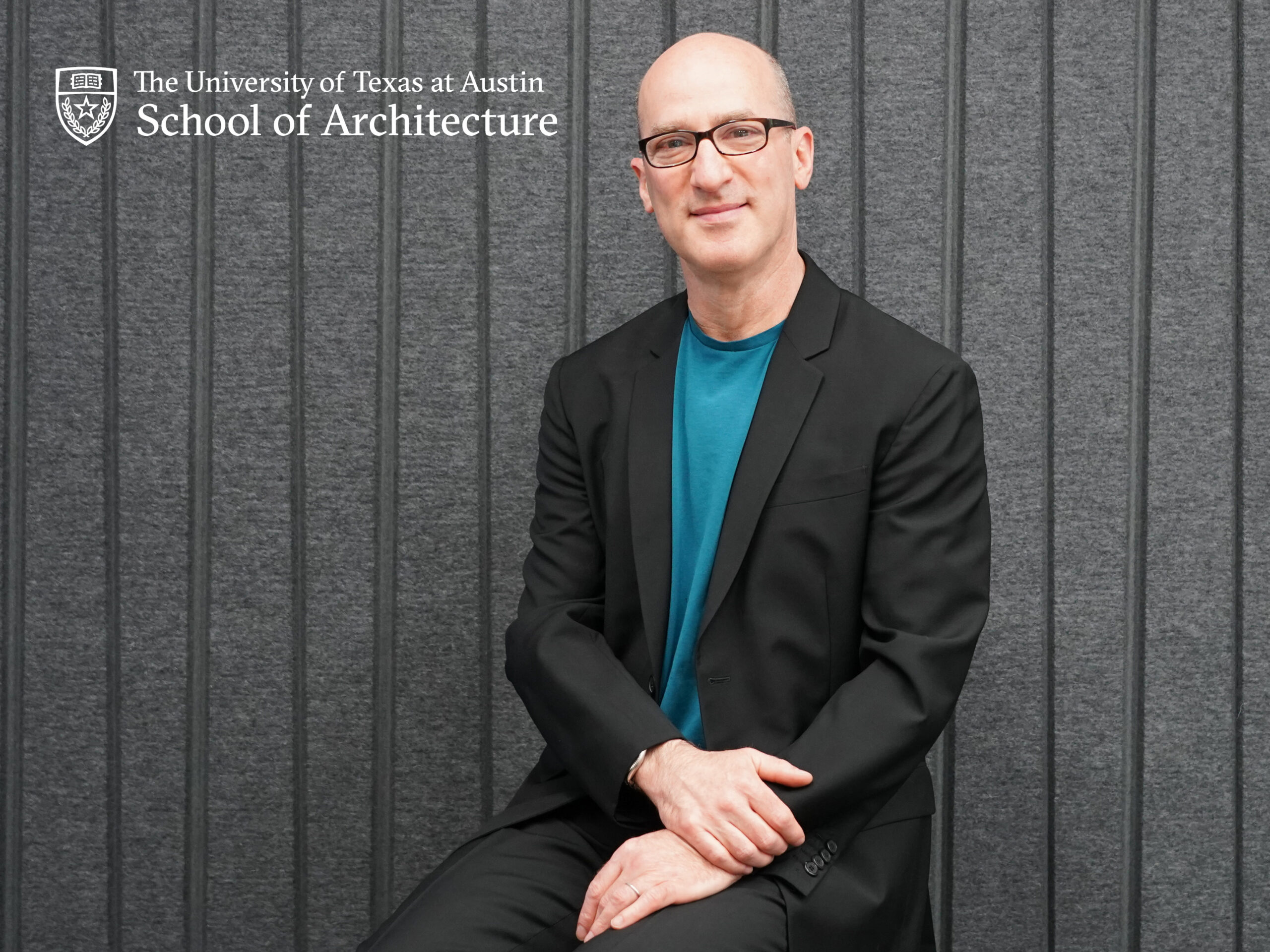 Headshot of Stephen Cassell against grey felt background. "UT Austin School of Architecture" logo in upper left corner.